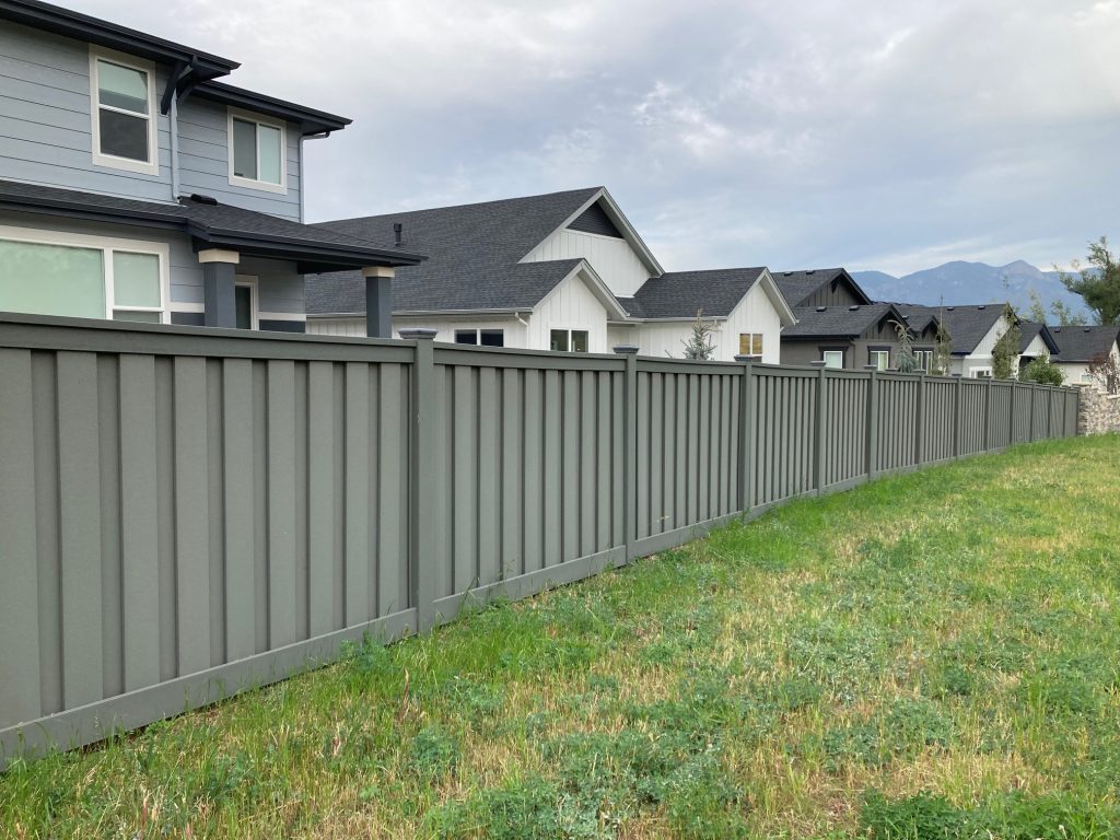 long gray fence in front of a group of homes on grassy yard